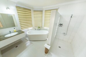 Un baño moderno con una bañera independiente, un espejo grande y una zona de ducha.