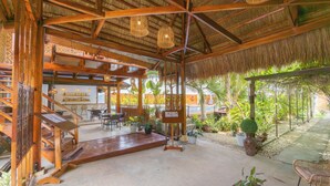 A spacious indoor area with a wooden staircase, seating arrangements, and a thatched roof. - Palms Cove Resort (Panglao)