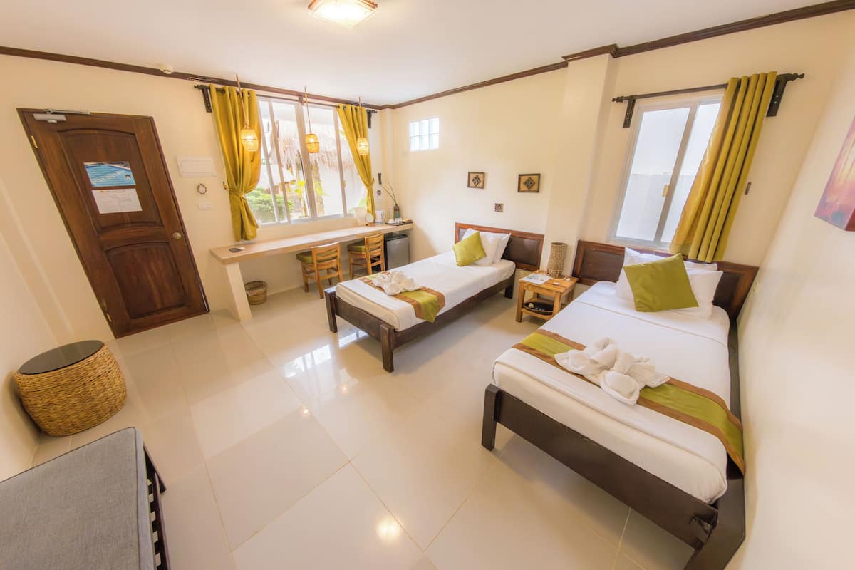 A hotel room with two beds, a desk, and a window with curtains.