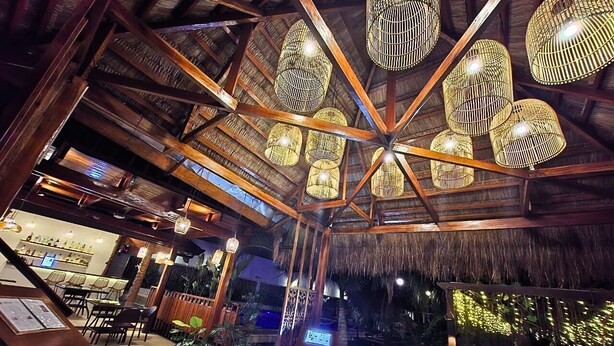 A restaurant with a thatched roof, wooden beams, and hanging wicker lamps. - Palms Cove Resort (Panglao)