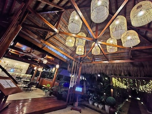 A restaurant with a thatched roof, wooden beams, and hanging wicker lamps. - Palms Cove Resort (Panglao)