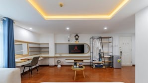 Een moderne hotelkamer met een bed, een bureau, een stoel, een televisie, een kledingkast en een tafeltje met spullen erop.