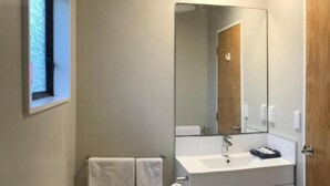 A compact bathroom with a toilet, a sink, a mirror, and a towel rack. - Adelaide Motel (Wellington)