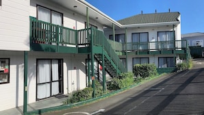 A two-story motel with a green exterior, a visible fire exit, and a parking lot with marked spaces. - Adelaide Motel (Wellington)