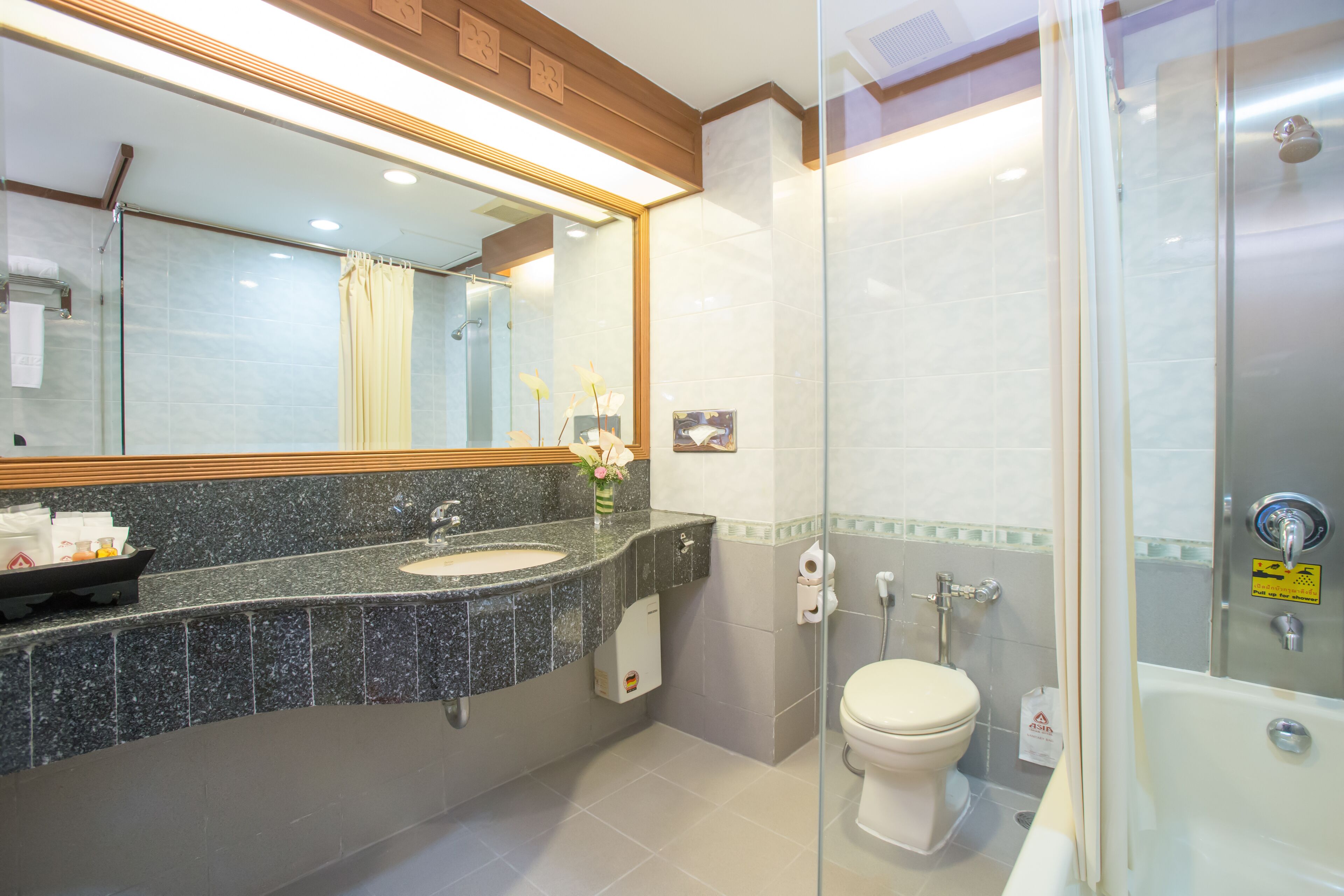A modern bathroom with a granite countertop, a glass shower enclosure, and a white toilet.