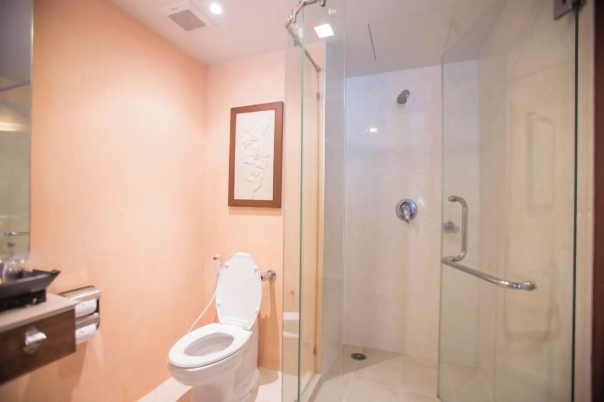 A modern bathroom with a glass-enclosed shower, a white toilet, and a framed artwork on the wall.