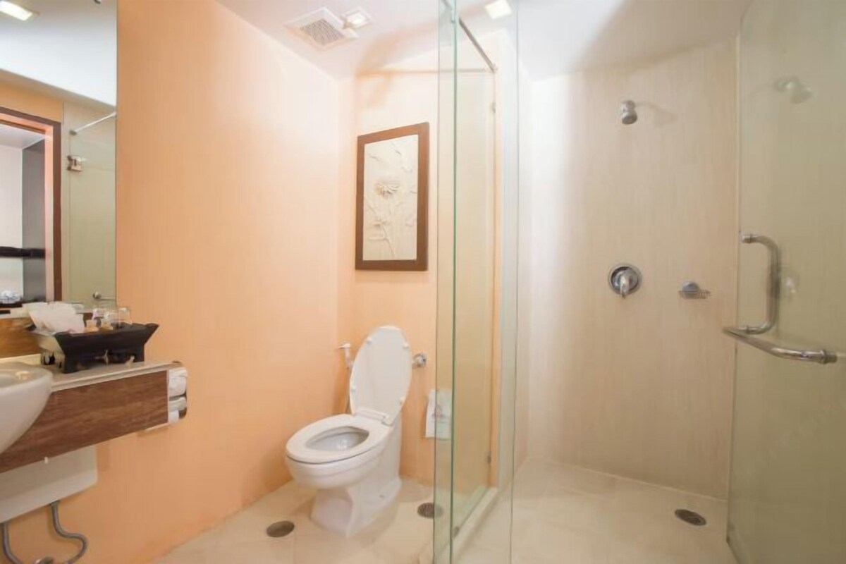 Un baño con ducha de vidrio, inodoro y lavabo con espejo.