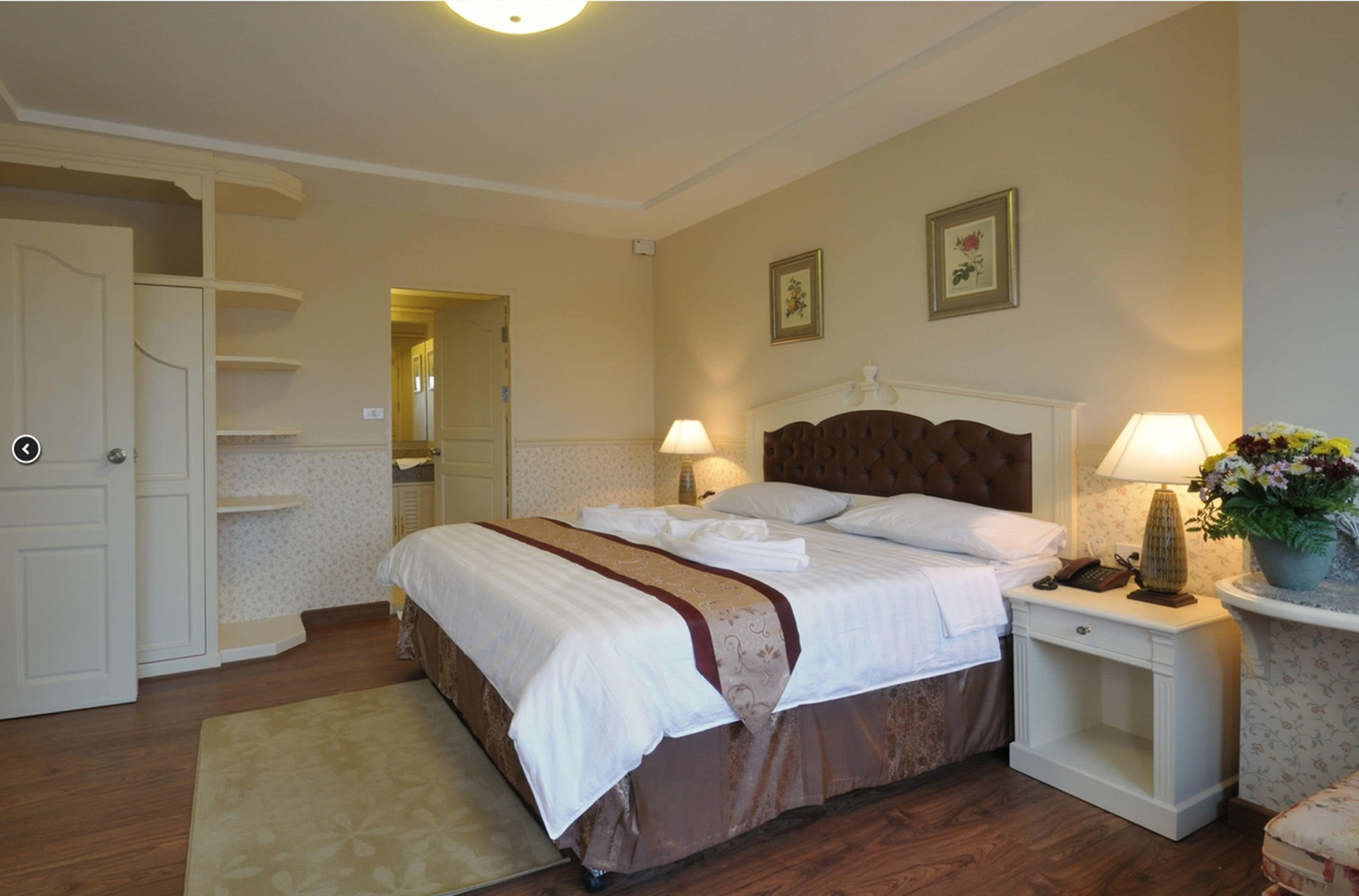 A neatly arranged bedroom with a large bed, bedside tables, a nightstand, and a door leading to a closet.