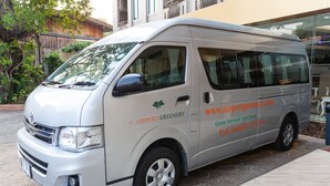 Een witte bestelwagen met de tekst 'The Airport Greenery' geparkeerd op een geplaveid stenen gebied.