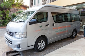 Een witte bestelwagen met de tekst 'The Airport Greenery' geparkeerd op een geplaveid stenen gebied.