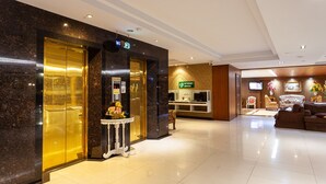 A hotel lobby with a reception desk, a TV, and a seating area. - The Airport Greenery Hotel (Chiang Mai)