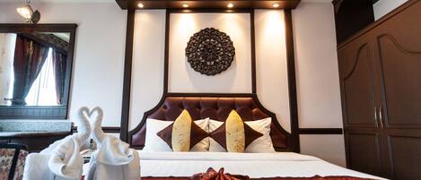 A hotel room with a large bed, a decorative wall hanging, and a wardrobe.
