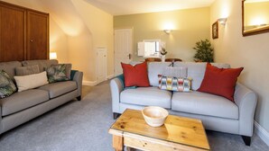 A living room with two sofas, a wooden coffee table, and a mirror on the wall. - The Uplands Serviced Apartments (St. Helier)