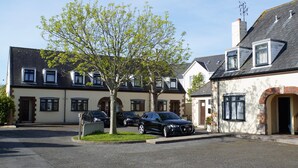 A residential street with two-story houses, a tree, and parked cars. - The Uplands Serviced Apartments (St. Helier)