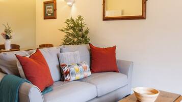A living room with a grey sofa, wooden coffee table, and a mirror on the wall.
