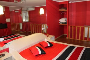 A hotel room with a bed, a bedside table, a mirror, a wardrobe, and a red wall. - Residencial Monte Carlo (Porto)