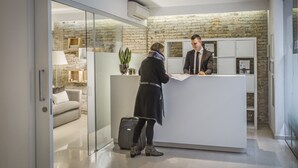 Un área de recepción con diseño moderno, que incluye un mostrador de recepción, un panel de vidrio y una pared de piedra al fondo.
