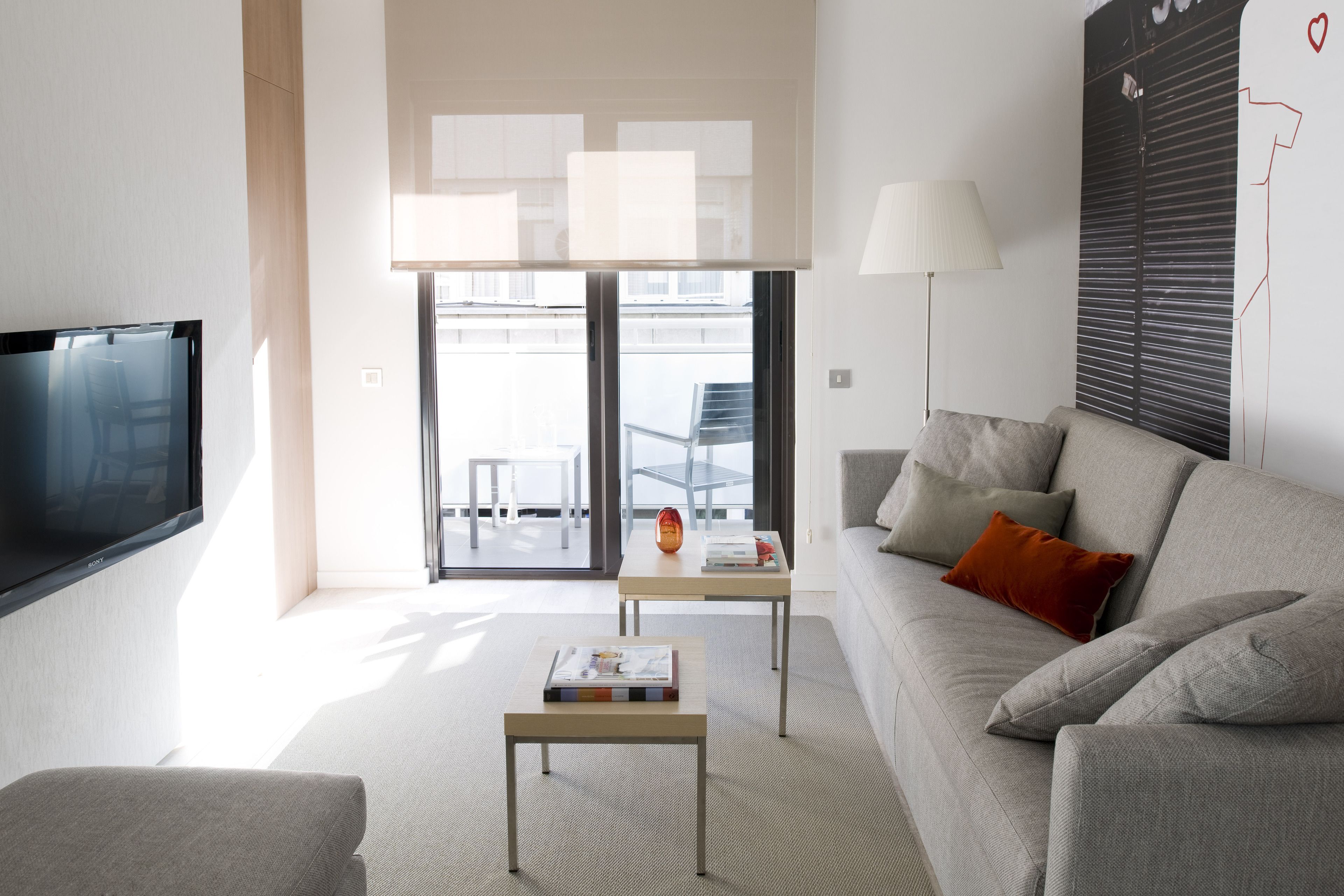 A modern living room with a flat-screen TV, a sofa, a coffee table, and a lamp.