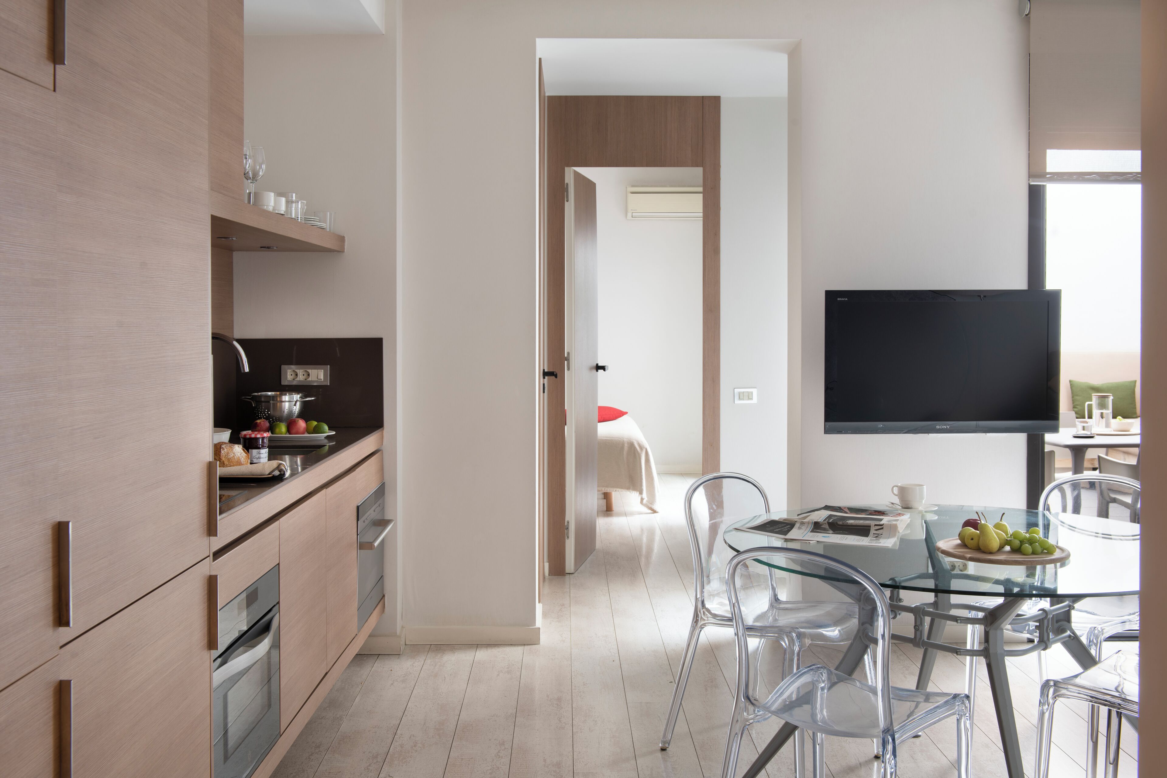 Una cocina moderna con comedor, televisor de pantalla plana y mesa de vidrio.