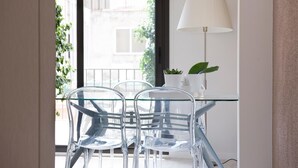Una habitación moderna con una mesa y sillas de vidrio, una lámpara y vistas al exterior.