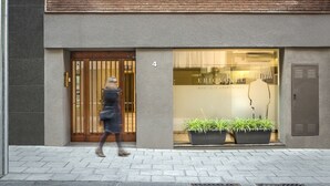 Un edificio moderno con fachada de ladrillo, entrada numerada y escaparate con plantas en macetas.