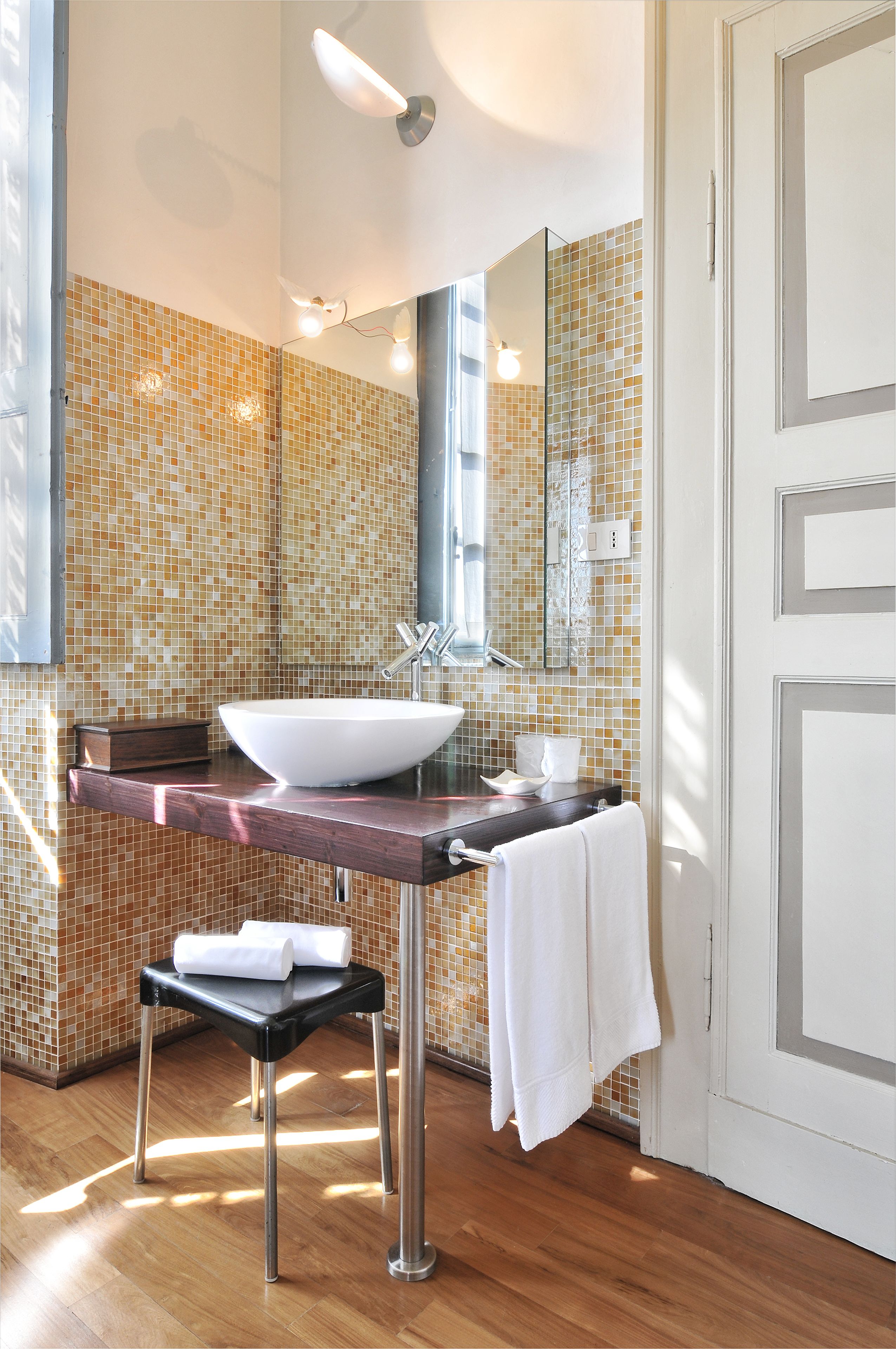 A bathroom with a large mirror, a vessel sink, and a tiled backsplash.