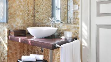 A bathroom with a large mirror, a vessel sink, and a tiled backsplash.