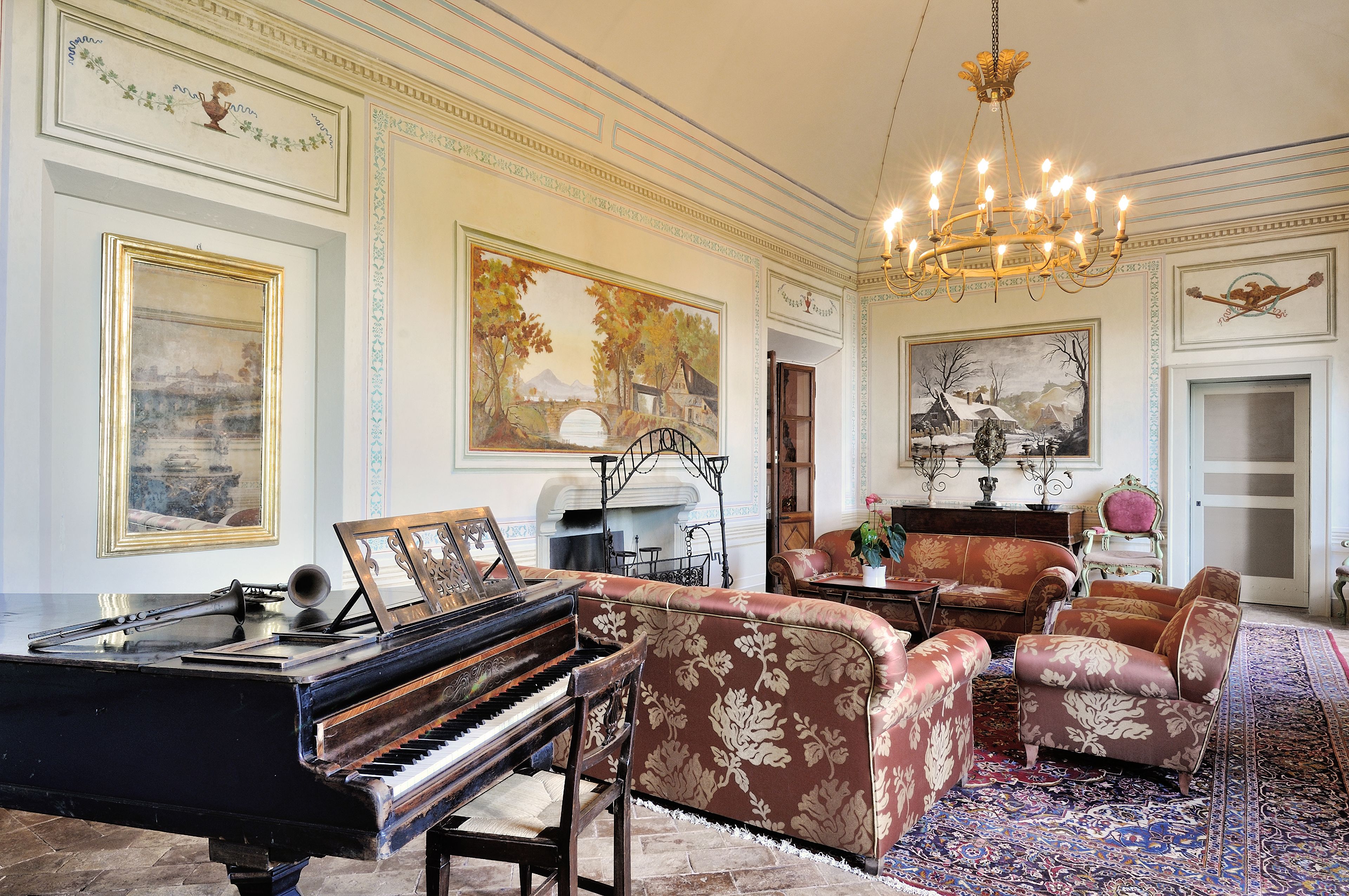 Una sala majestuosa con un piano de cola, lujosos sofás y una araña.