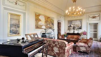 Una sala majestuosa con un piano de cola, lujosos sofás y una araña.