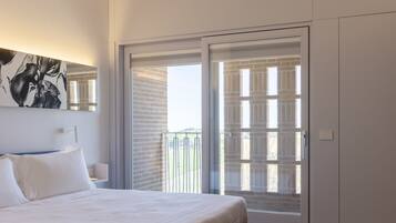 Een slaapkamer met een bed, een groot raam en een schuifdeur naar een balkon.