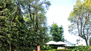 Ein formeller Garten mit einem zentralen Brunnen, ordentlich geschnittenen Hecken und einem Kiesweg.