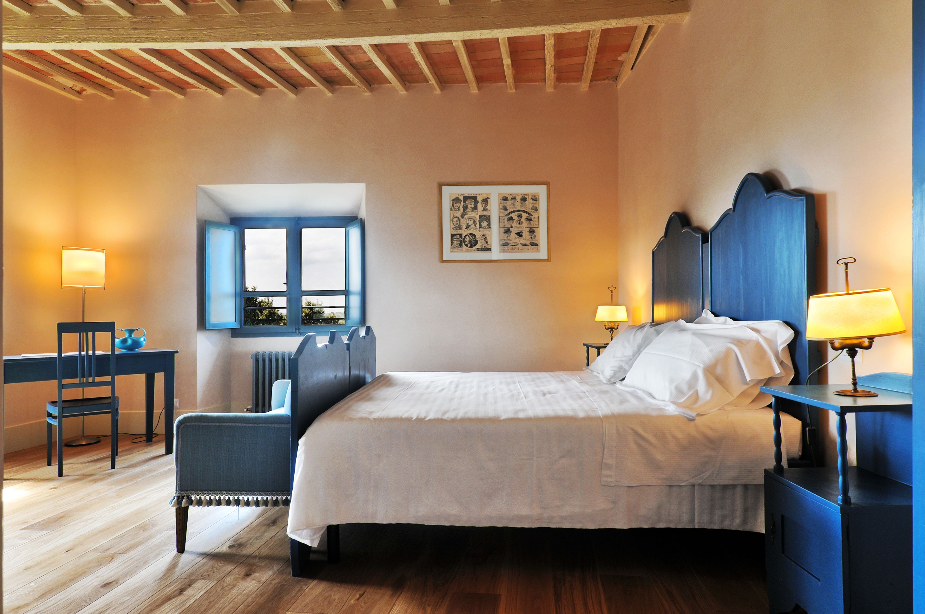 A bedroom with a large bed, a desk, a chair, and a window.
