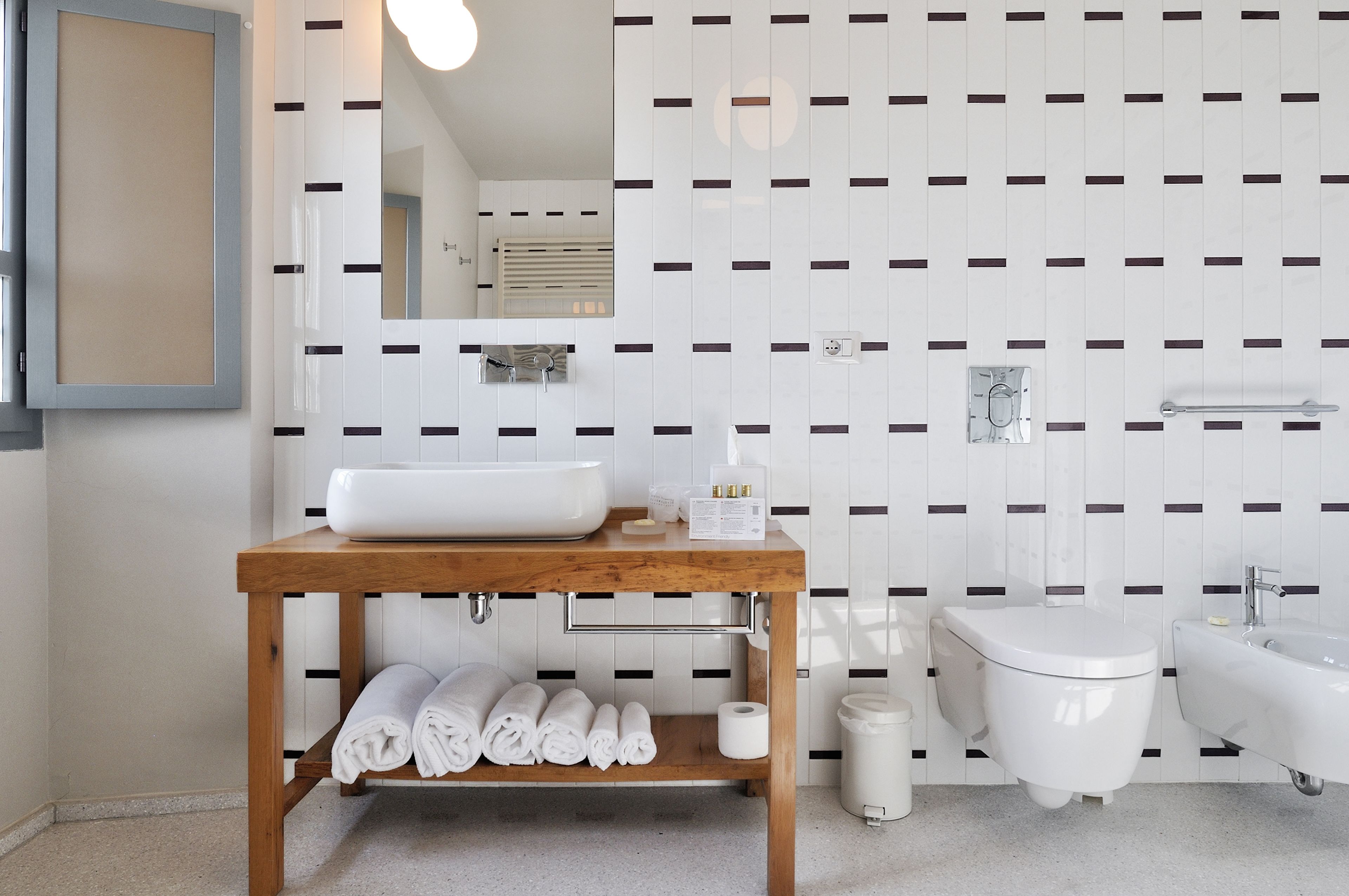 Un baño moderno con tocador de madera, lavamanos blanco y un bidé.