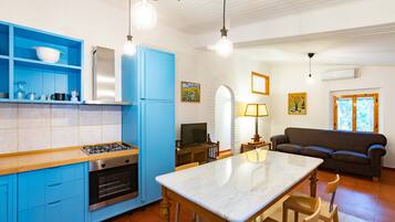 Una cocina moderna con armarios azules, una isla de mármol y una zona de comedor con sofá y lámpara.