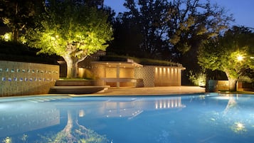 Una piscina al aire libre, sombrillas, sillones reclinables de piscina