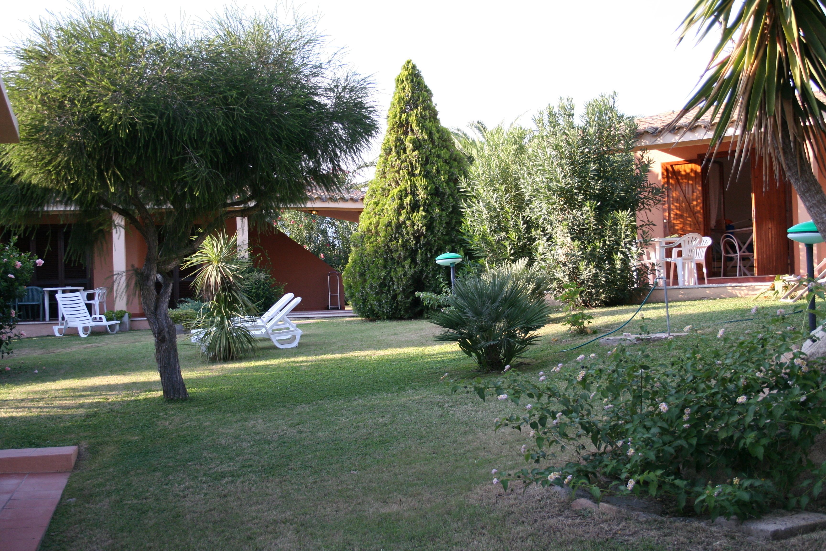A well-maintained garden with various trees and shrubs, outdoor furniture, and a patio area.