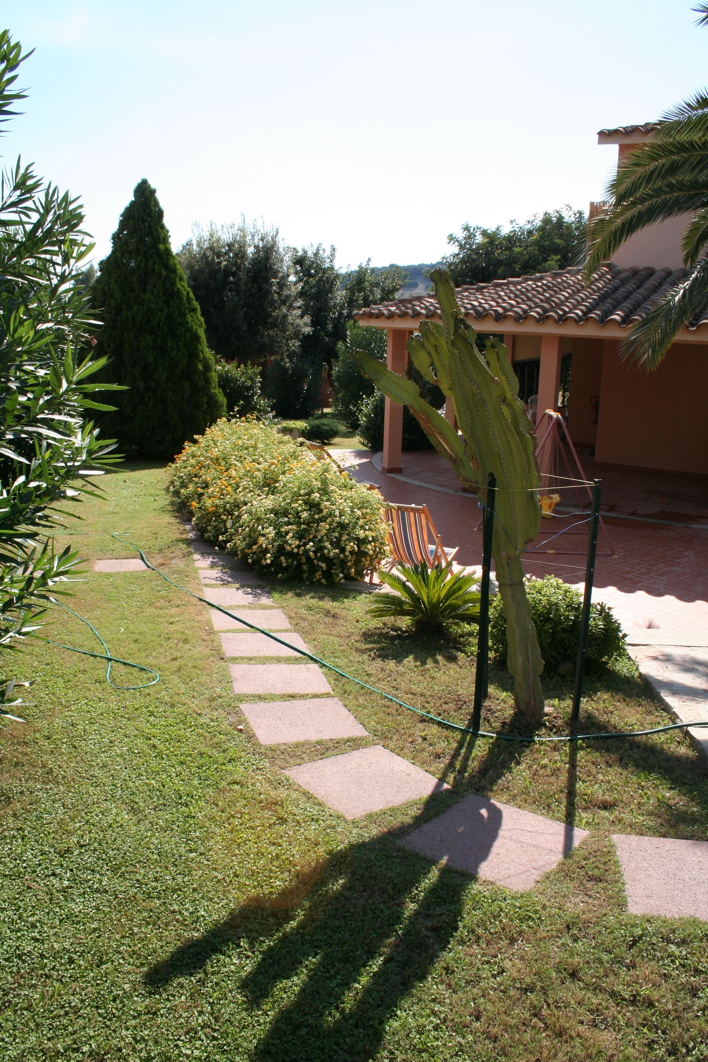 Ein Garten mit einem Pfad, der zu einem Gebäude mit einem Ziegeldach führt.