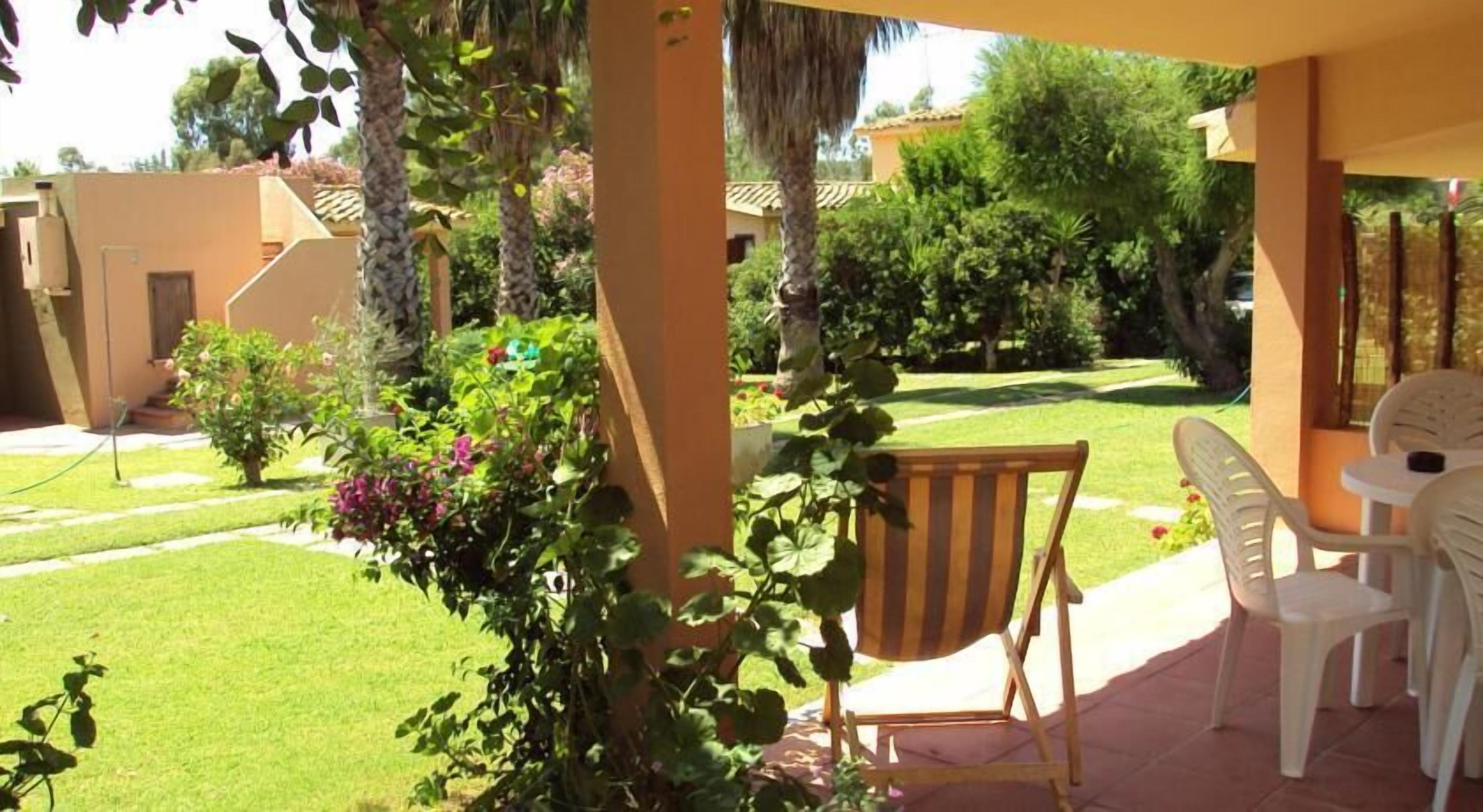A patio area with a table and chairs, surrounded by greenery and a well-maintained lawn.