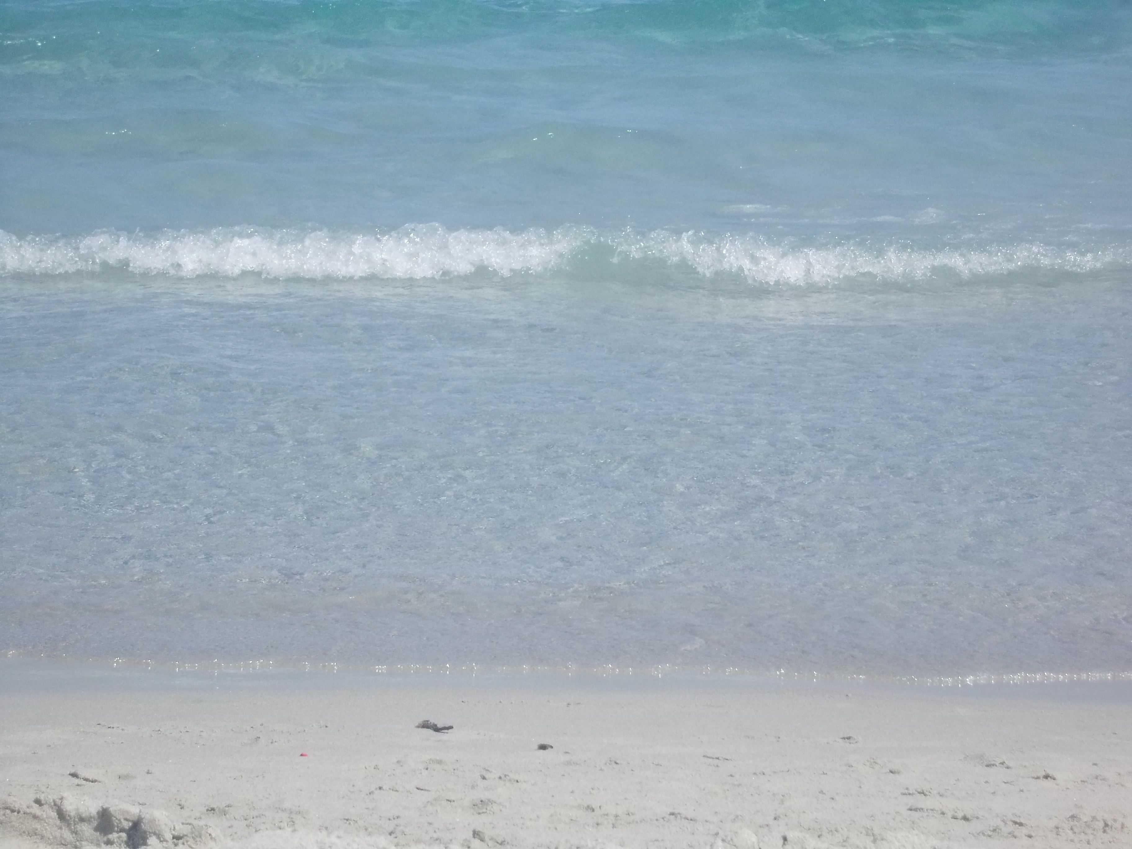 A beach with clear water and a sandy shore.