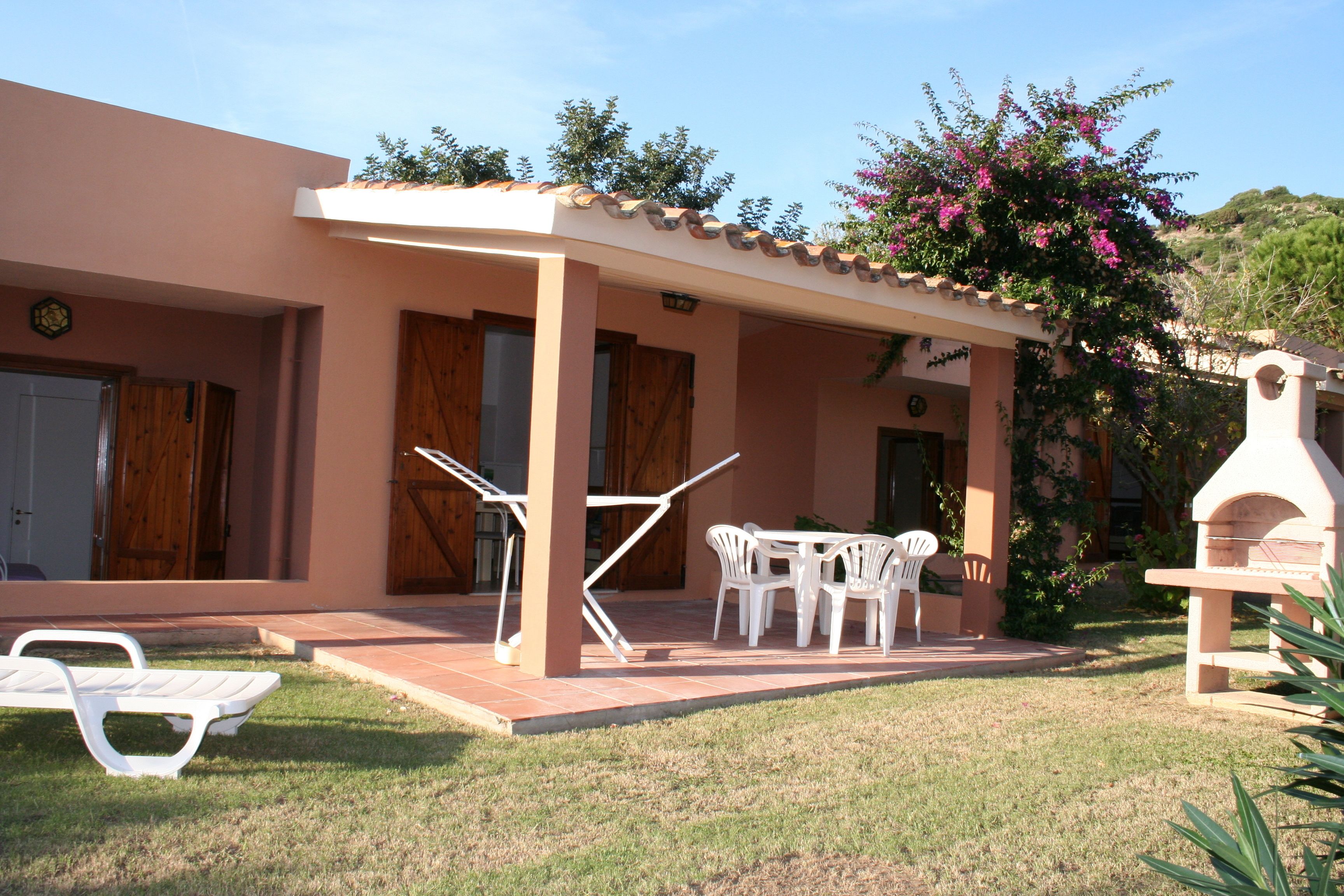 A building with a covered patio, outdoor seating, and a barbecue area.