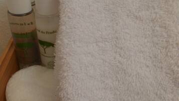 A wooden tray with a white towel, two bottles of lotion, and a round white object.
