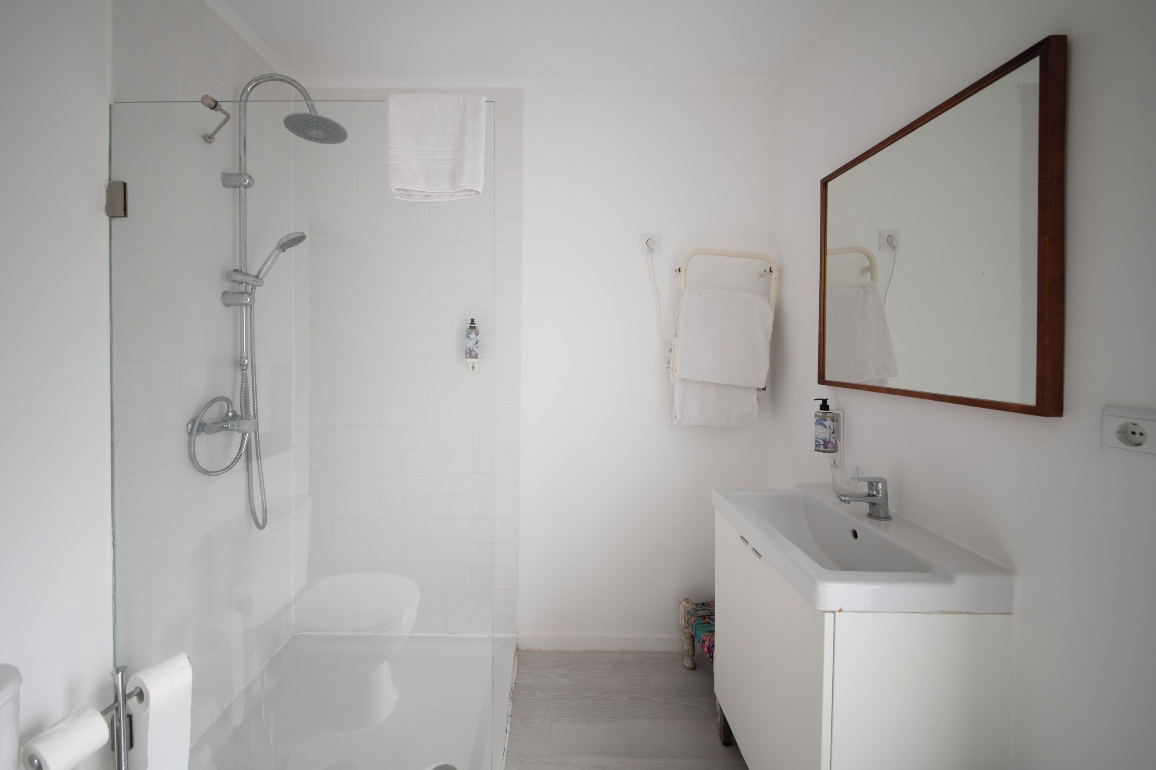 Un baño con ducha de vidrio, lavabo blanco y espejo.