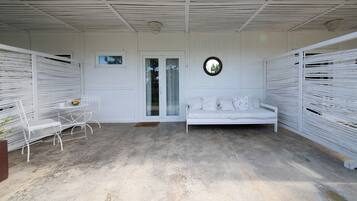 Una habitación blanca con un sofá blanco, una mesita con sillas y una ventana.
