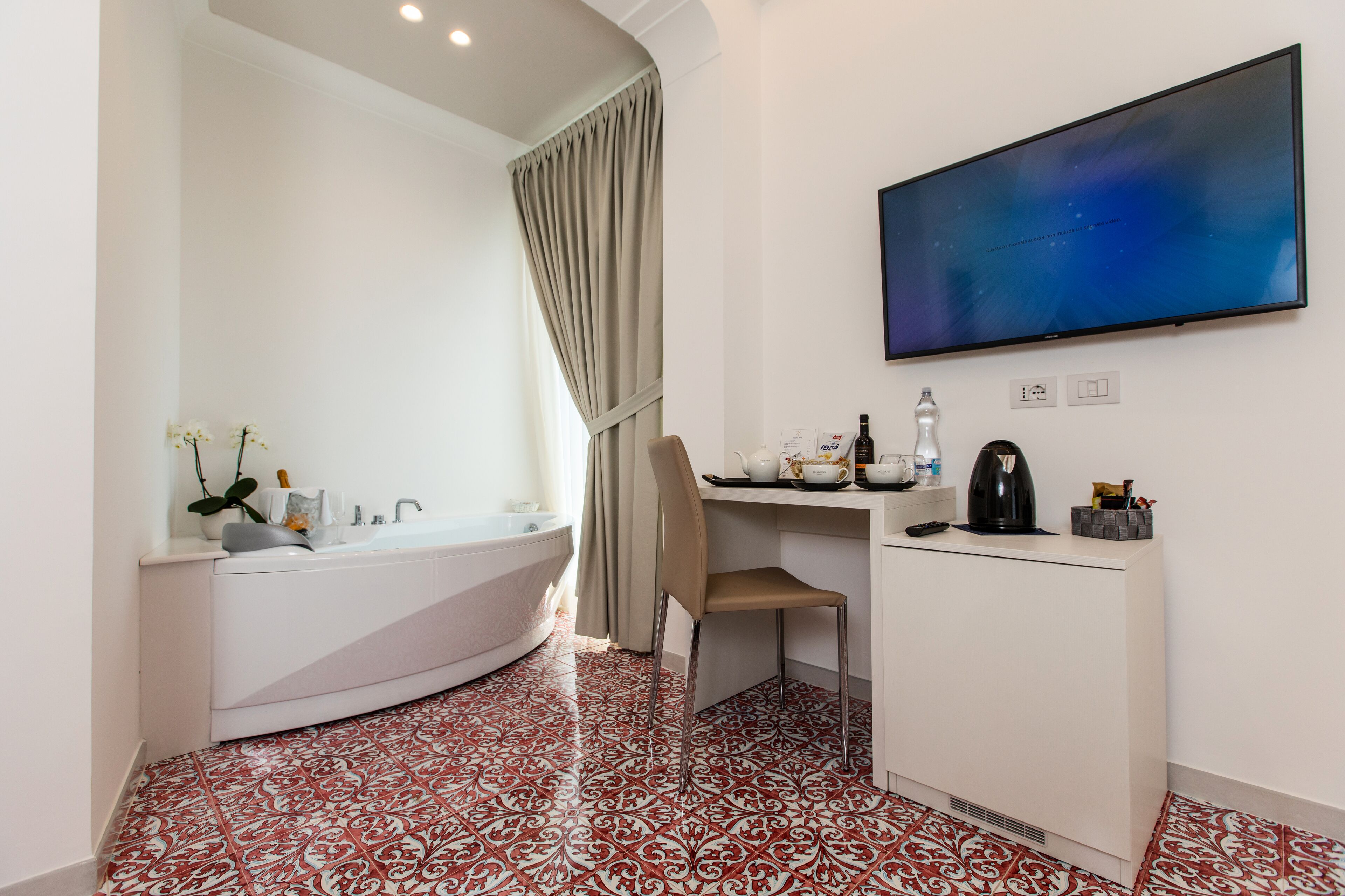 Un bagno moderno con una vasca freestanding, un mobile vanità con lavello e un'ampia TV a schermo piatto fissata al muro.