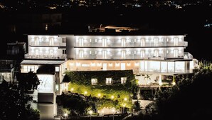 A multi-story building with balconies, large windows, and a well-lit facade at night. - Hotel Le Rocce (Agerola)