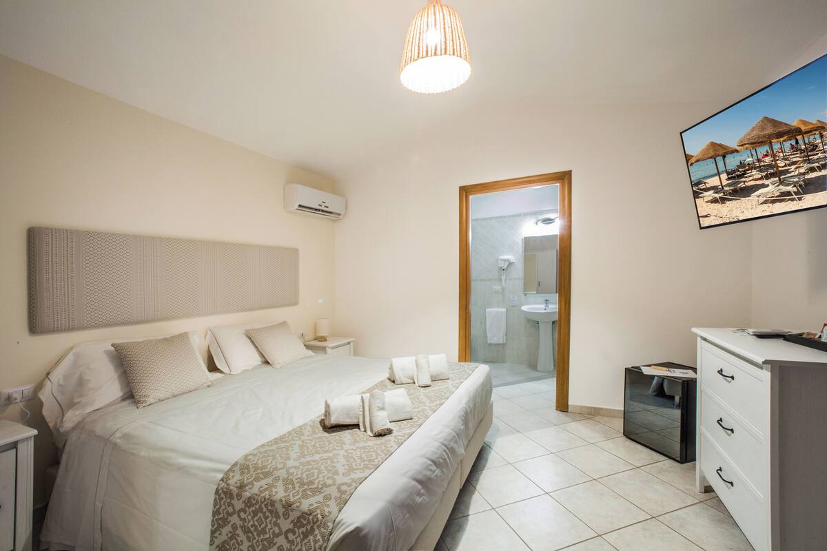 Ein Schlafzimmer mit einem großen Bett, Nachttischen, einem Schminktisch und einem Fernseher.