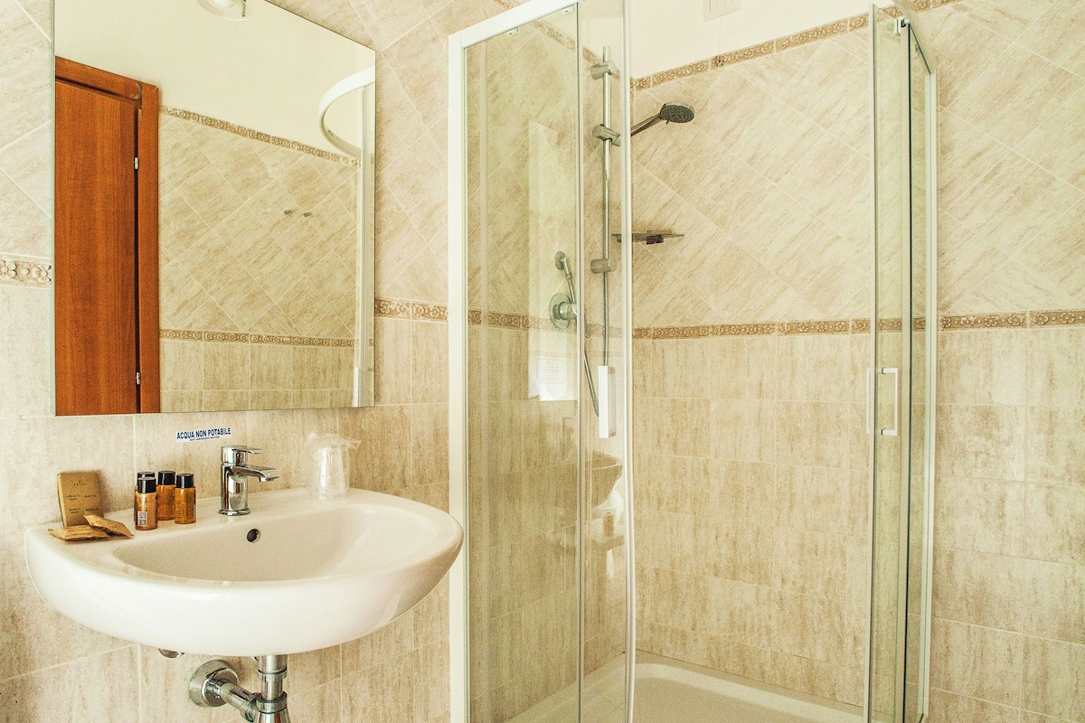 Une salle de bain avec une douche à parois de verre, un lavabo avec un miroir et des murs carrelés.