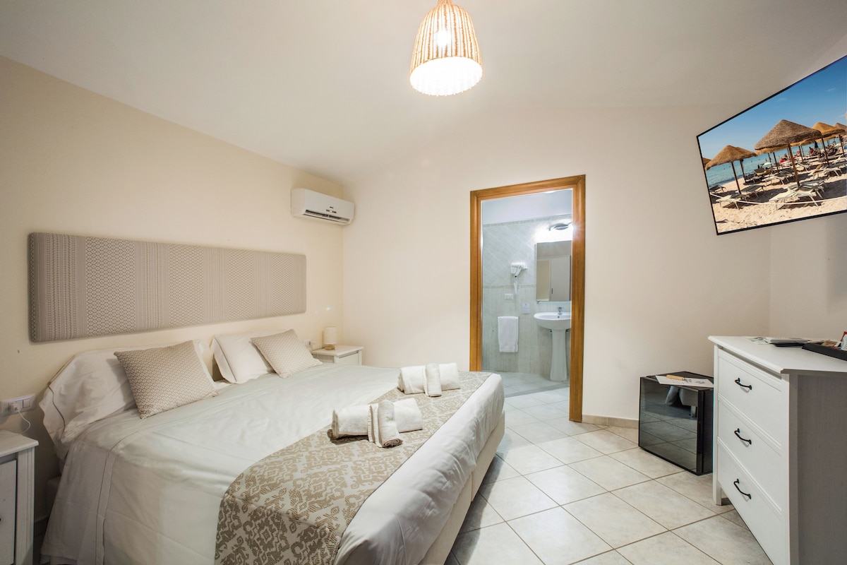 Une chambre à coucher avec un grand lit, des tables de chevet, une commode, un miroir et un téléviseur.