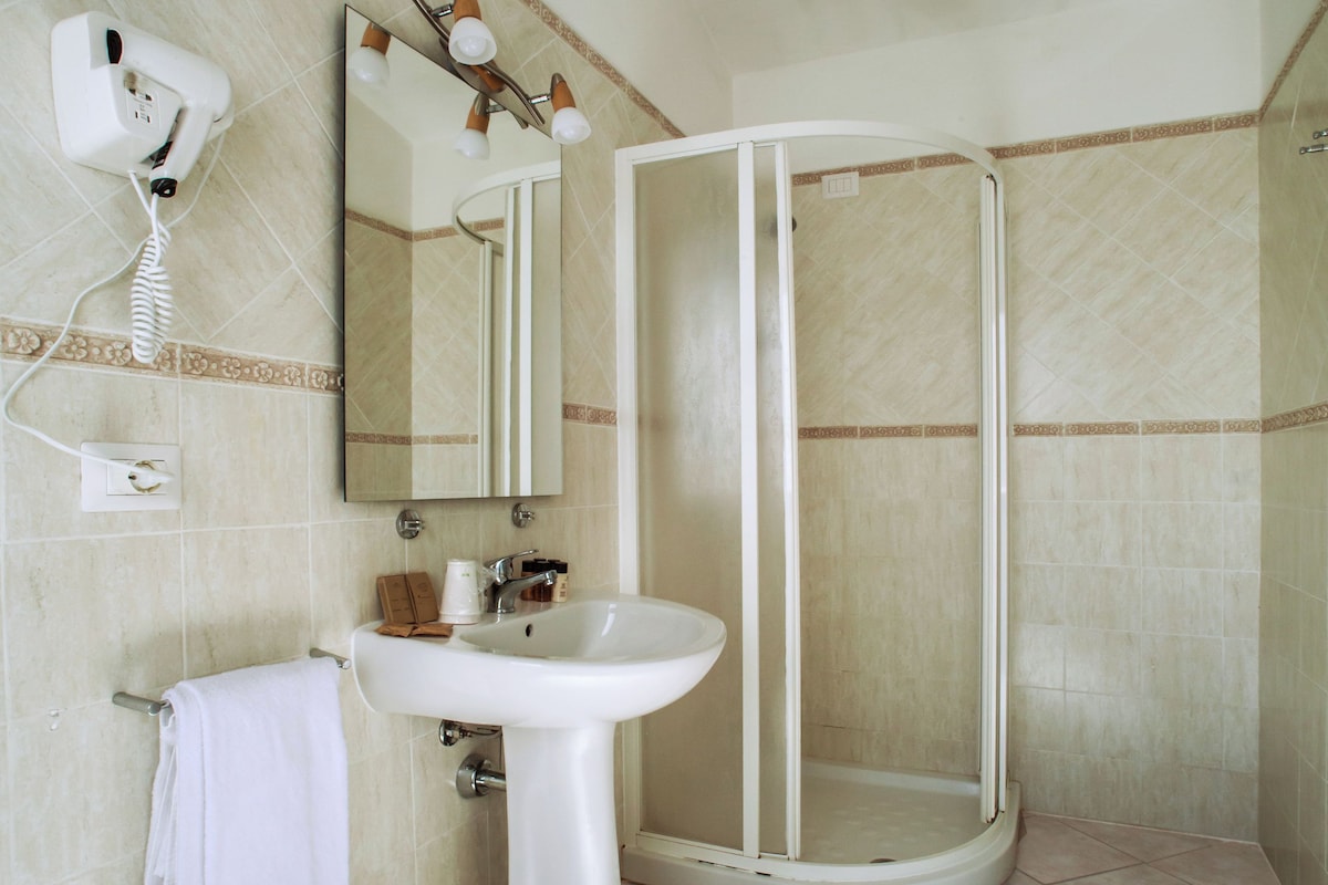 Une salle de bain équipée d’un lavabo, d’un miroir, d’un porte-serviettes et d’une cabine de douche.