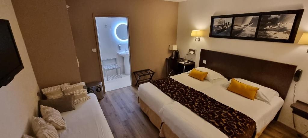 A hotel room with a bed, bedside tables, a desk, a chair, and a bathroom visible through an open door.